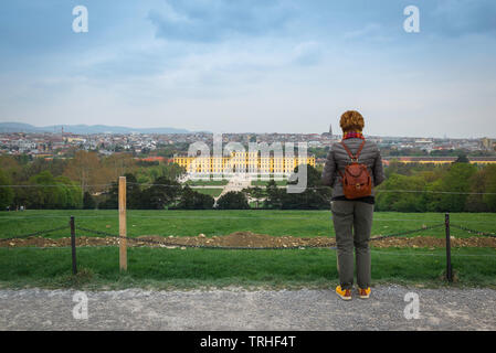 Weibliche Touristin, Rückansicht einer reifen Frau, die im Rucksack auf Schloss Schönbrunn und die Wiener Skyline, Wien, Österreich schaut. Stockfoto