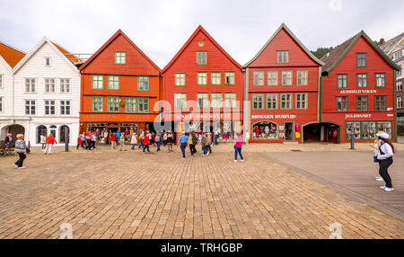 Touristen zu Fuß auf einem großen gepflasterten Platz vor dem Hintergrund der farbenfrohen Holzhäuser in der Hanseatischen Viertel Bryggen, Torget, der Deutschen Wharf, Stockfoto