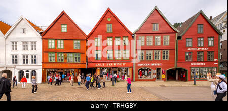 Touristen zu Fuß auf einem großen gepflasterten Platz vor dem Hintergrund der farbenfrohen Holzhäuser in der Hanseatischen Viertel Bryggen, Torget, der Deutschen Wharf, Stockfoto