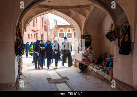 Eine Gruppe von Mädchen zu Fuß durch einen Torbogen in der Altstadt von Abyaneh, Iran. Die Stadt ist eine beliebte Touristenattraktion. Stockfoto