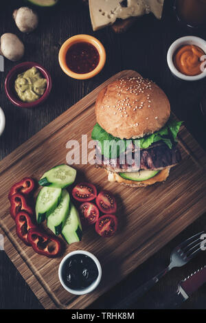 Leckere amerikanische Burger mit frischen Tomaten und Sauce serviert, Ansicht von oben Stockfoto