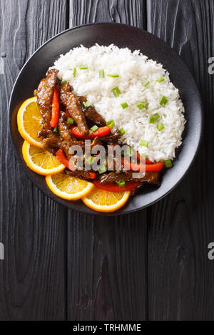 Rindfleisch mit Paprika orange Glasur mit Reis in der Nähe serviert auf einem Teller. Vertikal oben Ansicht von oben Stockfoto