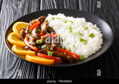 Im asiatischen Stil Rindfleisch mit Paprika in süß-saurer Sauce serviert mit Reis close-up auf einem Teller auf den Tisch. Horizontale Stockfoto