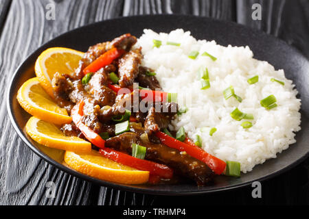 Gebratene asiatische Rindersteak mit Paprika in Soja orange Sauce serviert mit Reis close-up auf einem Teller auf den Tisch. Horizontale Stockfoto