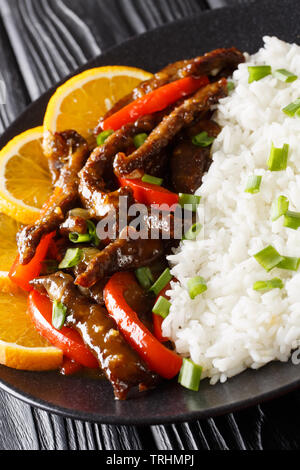 Lecker Geschnetzeltes Rindfleisch Steak mit Paprika orange Glasur mit Reis in der Nähe serviert auf einem Teller. Vertikale Stockfoto