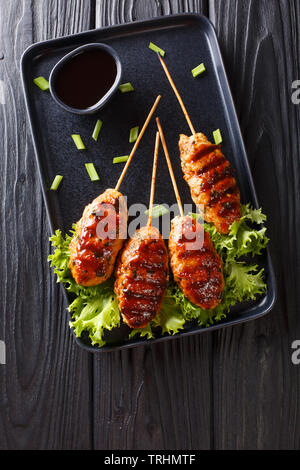 Tsukune japanische Huhn Frikadellen, aufgespießt und in der Regel über Holzkohle gegrillt Close-up auf einem Teller auf den Tisch. Vertikal oben Ansicht von oben Stockfoto