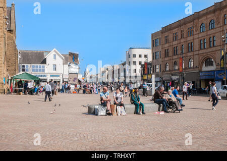 Menschen an einem sonnigen Tag sitzen, entspannen und wandern durch St Johns Square Blackpool Lancashire England Großbritannien Stockfoto