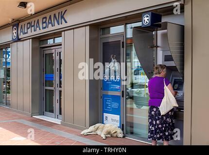 Eine Frau mit einem Geldautomaten zu einem Alpha Bank Filiale in Chalkidiki, Griechenland. Stockfoto