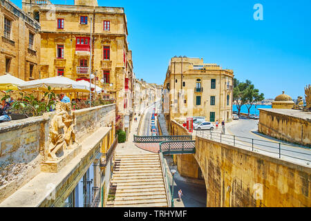 VALLETTA, MALTA - 19. JUNI 2018: Architektur der Altstadt mit kleinen Fußgängerbrücke des historischen Victoria Gate, Skulptur Dekoration der alten Gebäude Stockfoto