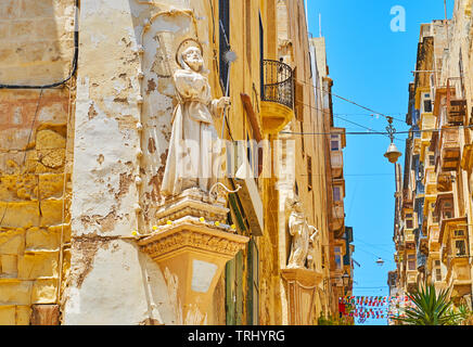 Die Ecke Wand Statuen des hl. Franz von Paula und der Hl. Franziskus von Assisi (im Hintergrund) Der bemerkenswerten Wahrzeichen von St. Lucia Street, Valletta, Malta. Stockfoto