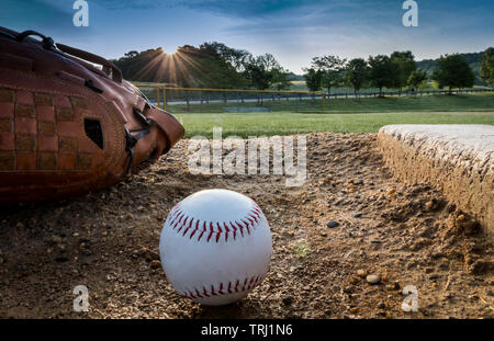 Baseball und Handschuh auf Krüge Damm am frühen Morgen Frühling Stockfoto