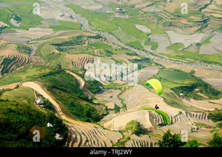 MU CANG CHAI, VIETNAM - 26. MAI 2019: Touristen Paragliding über Reisterrassen gewässert. Dies ist eine sehr berühmte Ort für Paragliding in Nordvietnam. Stockfoto