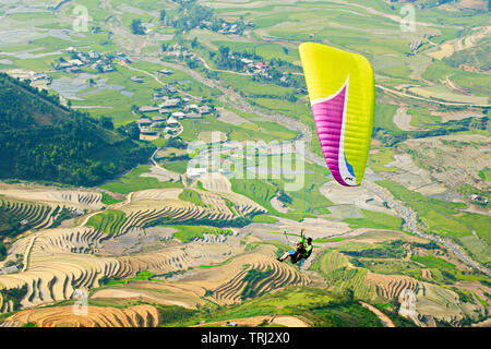 MU CANG CHAI, VIETNAM - 26. MAI 2019: Touristen Paragliding über Reisterrassen gewässert. Dies ist eine sehr berühmte Ort für Paragliding in Nordvietnam. Stockfoto