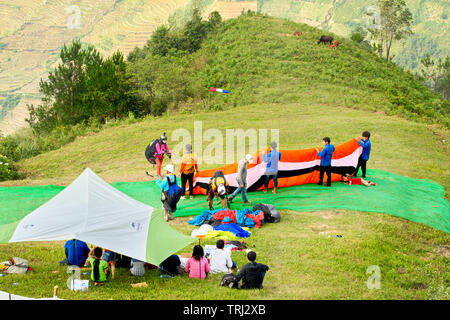 MU CANG CHAI, VIETNAM - 26. MAI 2019: Touristen Paragliding über Reisterrassen gewässert. Dies ist eine sehr berühmte Ort für Paragliding in Nordvietnam. Stockfoto