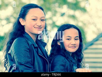 Porträt von zwei jungen Maori Schwestern getroffen, im Freien in einem Park. Stockfoto