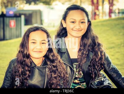 Porträt von zwei jungen Maori Schwestern getroffen, im Freien in einem Park. Stockfoto