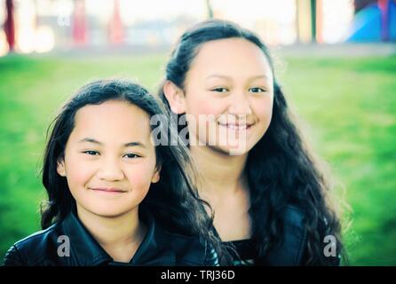 Porträt von zwei jungen Maori Schwestern getroffen, im Freien in einem Park. Stockfoto