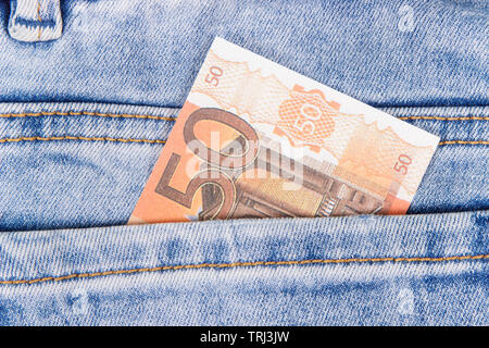 Geld in der Tasche von blauen Hosen. Finanzen und Banking Konzept Stockfoto