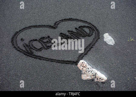Island Wort handschriftlich auf den schwarzen Strand sand in einem Herzen Stockfoto