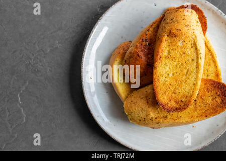 Knoblauch Brot getoastet und auf einer Platte geschnitten, mit einem grauen Fliesen Hintergrund Stockfoto