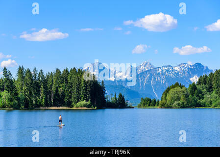 Mann auf SUP Board paddeln auf dem See in idyllischer östlichen Allgäu Stockfoto