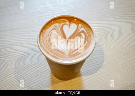 Heißer Kaffee Herzform in Schale braunes Papier auf Tisch Stockfoto