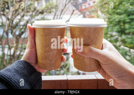 Zwei Hand, die eine heiße Tasse Kaffee aus Papier Stockfoto