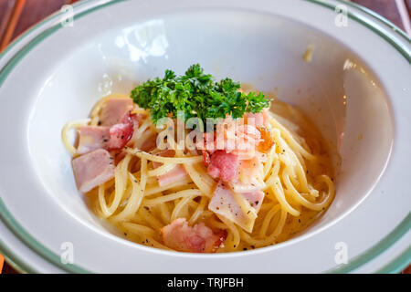 Spaghetti Carbonara mit Speck, Schinken und Gemüse in weiße Schüssel Stockfoto