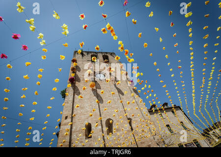 St Cyprien Kirche Glockenturm aus dem 12. Jahrhundert mit festlichen Bunting an einem heißen Sommertag. St Cyprien, Dordogne, Frankreich Stockfoto