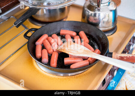 Kochen Frühstück mit Würstchen in der Pfanne Pfanne mit Holz- und Wendeeinheit Stockfoto