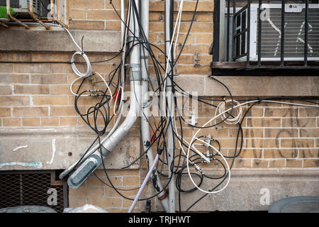 Einer Ratte Nest von Kabel und Leitungen für Telefon, Internet und andere Dienstprogramme auf der Fassade eines Mehrfamilienhauses in Brooklyn in New York am Samstag, 1. Juni 2019. (© Richard B. Levine) Stockfoto