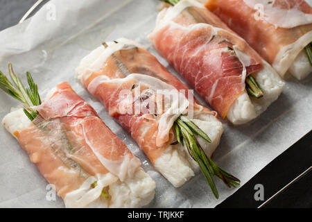 Vier Filets von Pollack Pollachius pollachius, dass in Zitronensaft und zerdrückten Knoblauch mariniert worden sein, bevor eingewickelt wurde in Parma Schinken mit Stockfoto