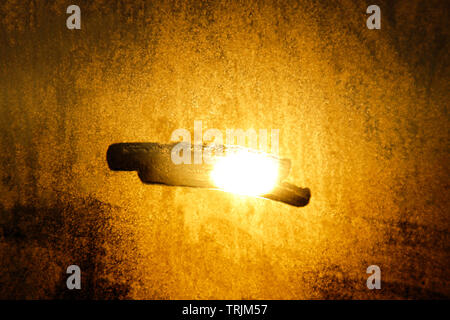Ein Sonnenstrahl durch die Fensterläden aus Holz kommt, leuchtet Staub auf der Innenseite der einen dunklen Raum. Close Up, selektive konzentrieren. Vintage Hintergrund. Stockfoto