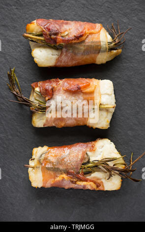 Drei gekocht Filets von Pollack Pollachius pollachius, dass in Zitronensaft und zerdrückten Knoblauch, bevor in Parmaschinken w eingewickelt zu werden, mariniert worden sind Stockfoto