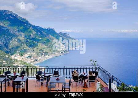 Restaurant im Freien speisen oder Getränke mit Blick zwei Frau Touristen entspannen Sie sich auf einem Cafe Terrasse hoch über der Amalfiküste in Ravello Stockfoto