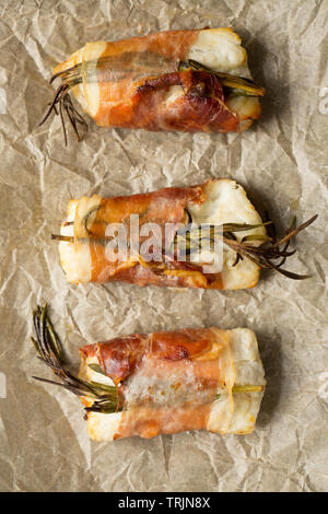 Drei gekocht Filets von Pollack Pollachius pollachius, dass in Zitronensaft und zerdrückten Knoblauch, bevor in Parmaschinken w eingewickelt zu werden, mariniert worden sind Stockfoto