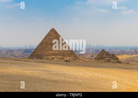 Kamelkarawane vor der Großen Pyramide des Menkaure in der Pyramide von Gizeh Komplex auf Hintergrund Kairo Skyline der Stadt. Stockfoto