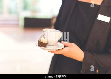 Nahaufnahme von Kellnerin holding Tasse Kaffee und kleine Cookie. Platz für Kopieren. Stockfoto