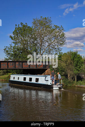 Ein "Traum" für einige ein, einen schmalen Kanal Boot unter einer Eisenbahnbrücke auf der Trent und Mersey Canal an einem Frühlingstag in Cheshire. Stockfoto