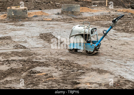 Plate compactor auf dem Boden an der Baustelle. Schwingende hammer Power Tool, Jumping Jack Maschine komprimieren Boden Stockfoto