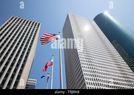 Fliegen amerikanische Flaggen von hohen Wolkenkratzern in Houston, Texas, USA umgeben. Stockfoto