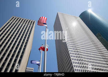 Fliegen amerikanische Flaggen von hohen Wolkenkratzern in Houston, Texas, USA umgeben. Stockfoto