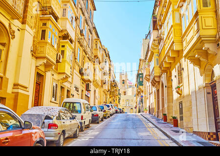 SENGLEA, MALTA - 19. JUNI 2018: Spaziergang auf den ruhigen Victoria Street mit Blick auf den traditionellen Wohn- bauten und den Glockenturm von St. Philip Kirche auf b Stockfoto