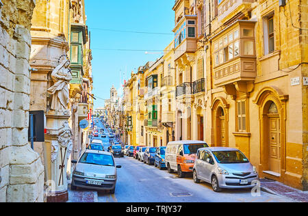 SENGLEA, MALTA - 19. Juni 2018: Die malerische historische Straße mit alten Bauten, mit Schnitzereien, Skulpturen, traditionellen und Türen aus Holz Stockfoto