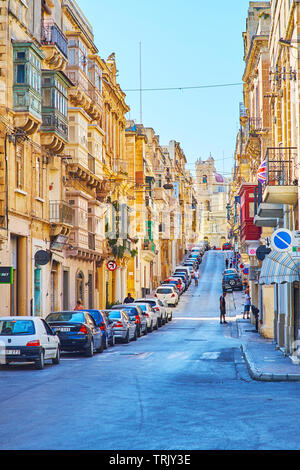 SENGLEA, MALTA - 19. Juni 2018: Das Alte Hügelland Victoria Street ist mit alten Wohngebäuden gesäumt und es endet mit Glockenturm von St. Philip Kirche, Stockfoto