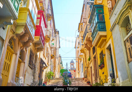 Die Wohn häuser in engen hügeligen Straße von Senglea mit farbenfrohen Malteser Balkone, geschnitzten Holztüren und Blumen in Töpfe entlang der Treppe, Malz Stockfoto