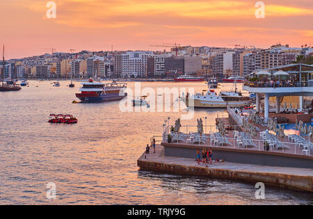 SLIEMA, MALTA - 19. Juni 2018: Die feurigen Himmel über dem Hafen von Sliema Resort mit Blick auf den kleinen Strand und modernen touristischen Viertel auf Backgr Stockfoto