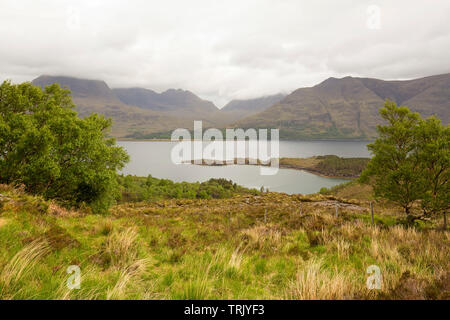 Misty Landschaft mit Wolken über Berge, Saum Loch Torridon und goldene Gräser in den schottischen Highlands hängen Stockfoto