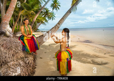 Zwei junge Mädchen (MR) ist im traditionellen Outfit für kulturelle Zeremonien ein Foto mit einem Smartphone auf der Insel Yap in Mikronesien. Stockfoto