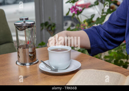 Winter tee Konzept. Frau Hände. Mädchen gießt Zitrusfrüchte Tee mit Zitronen und Orangen aus transparentem Glas Teekanne in eine Tasse. Stockfoto